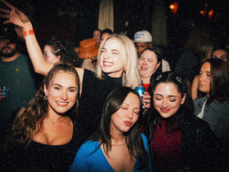 Friends dancing indoors under red lighting at a Bump & Grind party