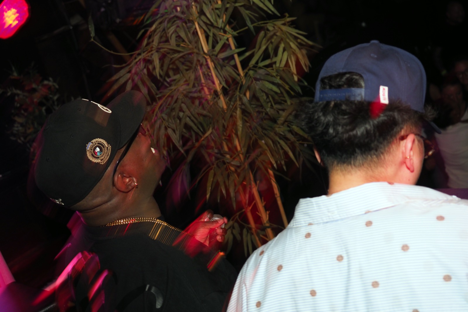 Two guests in caps sharing a moment near the DJ booth