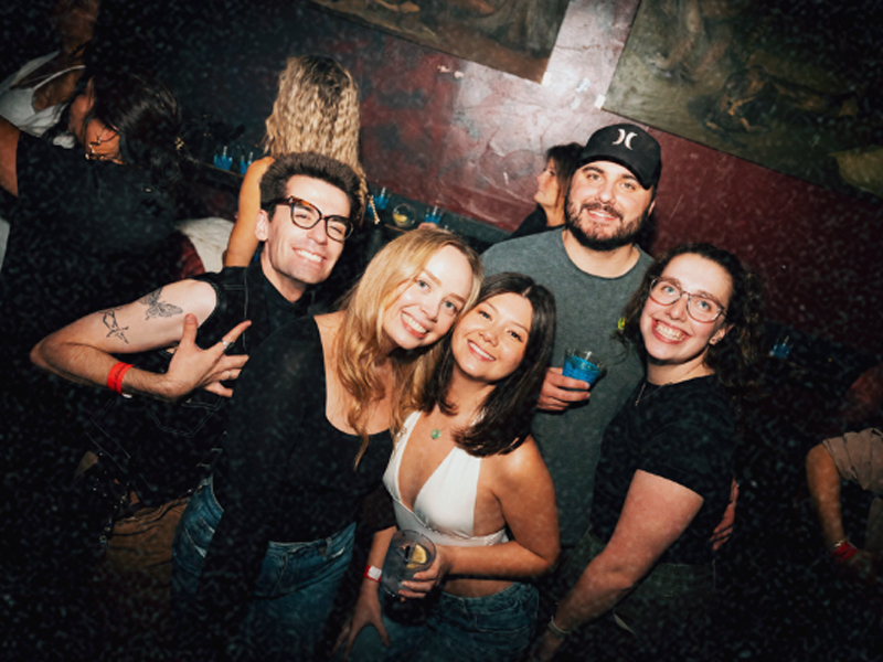 A group of friends smiling together at the bar during a Bump & Grind night